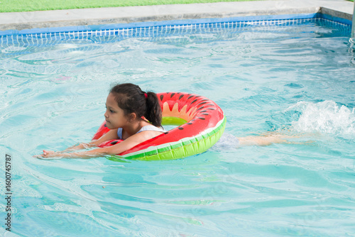 Indian Girl child using tube float in water and learning swimming in the pool. 