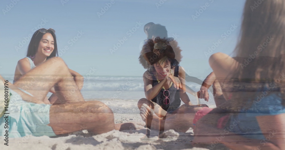 Fototapeta premium Relaxing group of adults and girl sitting on sandy shoreline, with pink sunglasses and beach towel