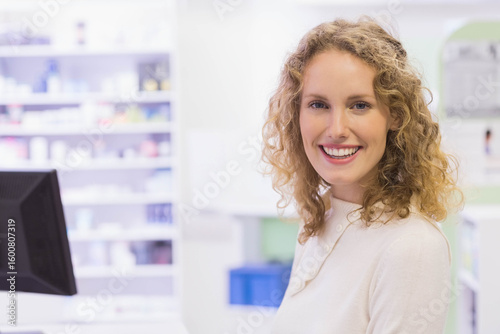 Free Download Female pharmacy staff smiling while checking computer monitor and organizing shelves, copy space - GFXLoad