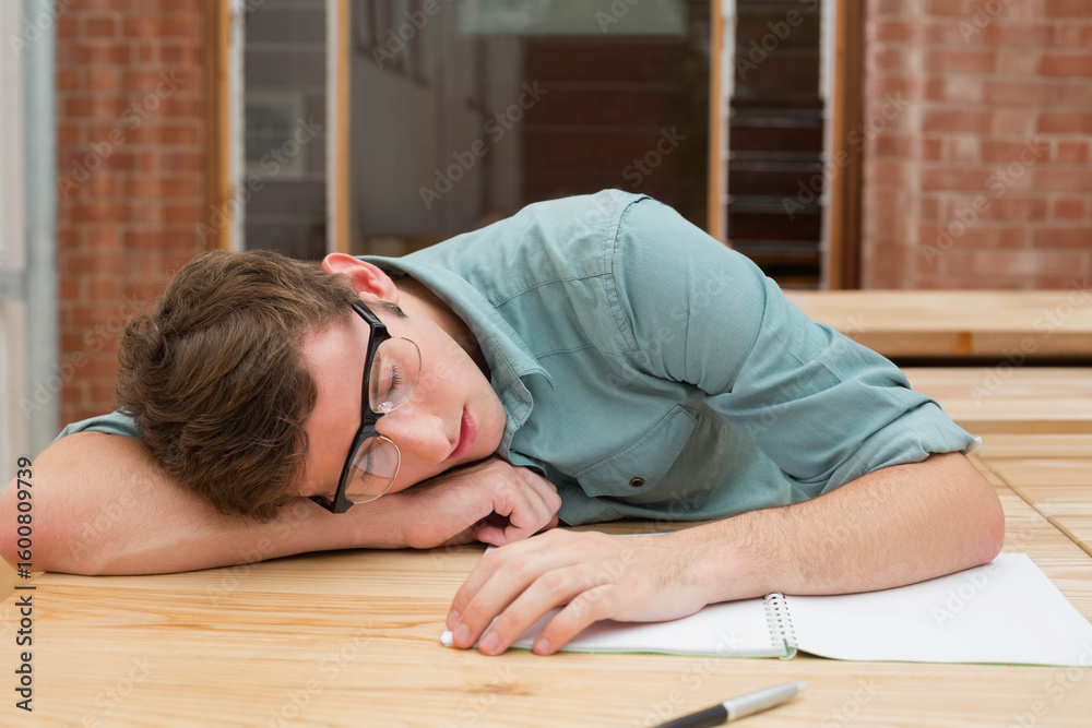 Obraz premium Spiral notebook and pen resting on wooden table beside exposed brick wall and doorway, copy space