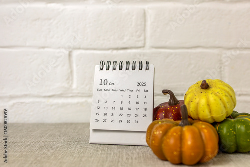A desktop calendar for October 2025 and a pumpkin on the table. Halloween is coming soon.