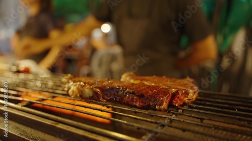 Close up of juicy steak cooking on open flame grill with orange glow, low angle, Street Food Concept