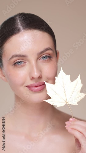 Portrait of beautiful young woman with autumn leafs. Healthy clean fresh skin natural make up beauty eyes. Slow motion, vertical video