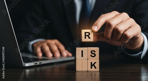 Navigating Risks: A professional, in a dark suit, is seen meticulously arranging a risk block as he ponders the details of a laptop, depicting business evaluation.