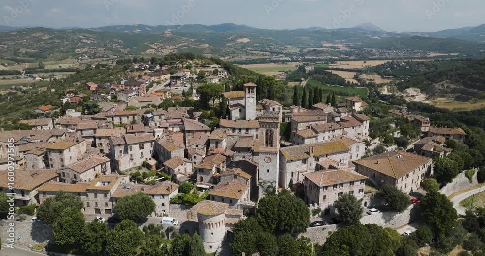Aerial view of the clustered buildings with red tiled roofs in Corciano, nestled amid rolling green hills and lush trees, Corciano, Perugia, Italy. Aerial view of the clustered buildings with red tiled roofs in Corciano, nestled amid rolling green hills and lush trees, Corciano, Perugia, Italy.