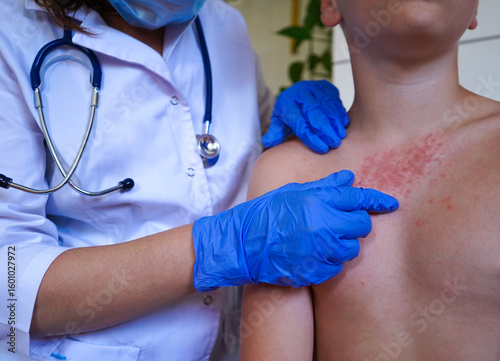 A boy with a red rash is being checked by the physician.