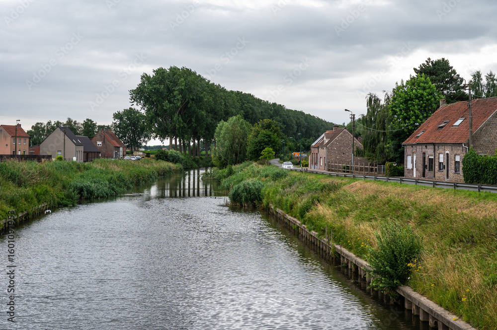 Fototapeta premium Residential houses at the green banks of the canal in Zomergem, East Flanders, Belgium