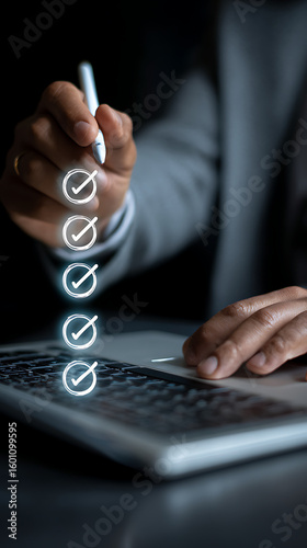Person using stylus to mark completed tasks on digital checklist above laptop task completion digital interface
