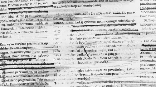 Close up of heavily marked and scribbled text on paper with black ink lines and smudges creating