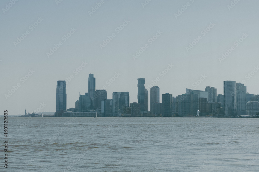 Fototapeta premium City skyline showcases modern architecture along the waterfront during a clear day with minimal clouds. The view of the Jersey side of the Hudson River from New York. side