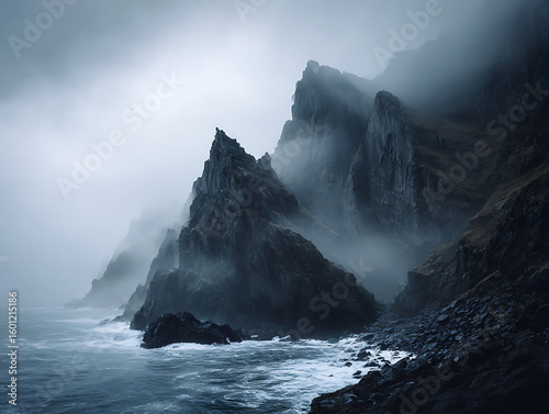 Dramatic jagged cliffs emerging from misty ocean fog