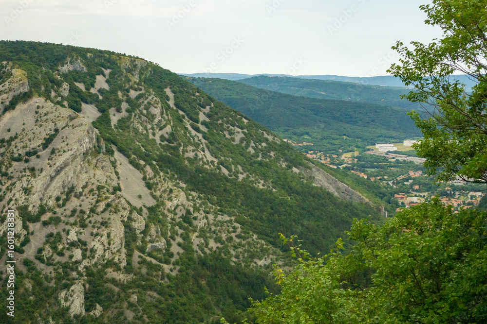 Fototapeta premium Mountains in trieste area italy, green hilly landscape with rocky slopes and distant town, scenic view of italian countryside, concept of travel destination, tourism, landscape photography