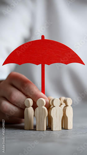 Red umbrella protecting wooden figures from overhead protection security