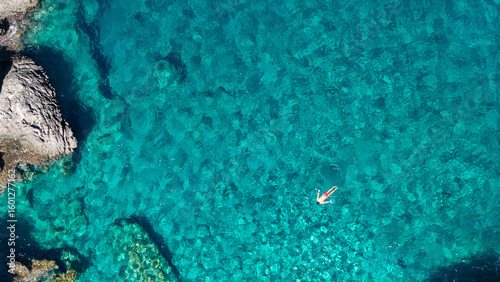 Aerial View of Swimmer in Turquoise Clear Sea Near Rocky Shore. Foneas beach in Messiniaki Mani
