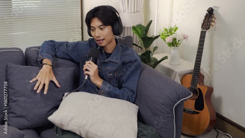 Cheerful radio host showing recording podcast with colleague having fun in the podcast studio at home talking and recording.