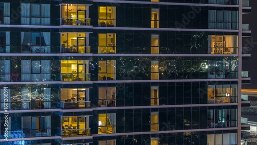 Glowing apartment windows at night in glass skyscraper timelapse