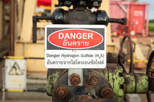 Danger of Hydrogen sulfide gas caution sign (In English and Thai text), the label on the gas and crude oil production wellhead that operated in the oilfield. Industrial safety sign object.