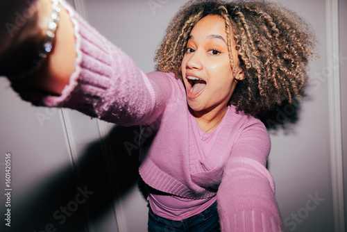 Woman joyfully capturing a selfie in a pink sweater