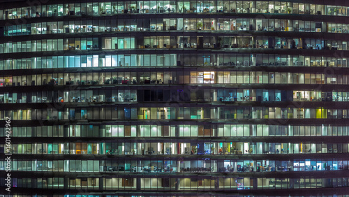 Working evening in glass office building with numerous offices with glass wal...