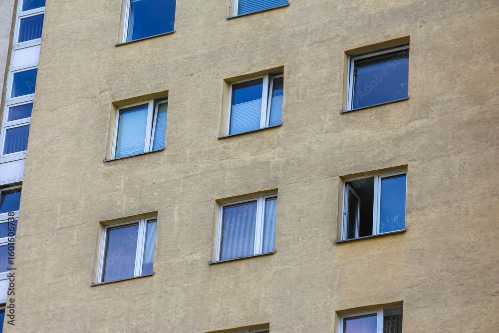 Fototapeta premium Multi-story residential apartment building with blue accents and balconies against clear sky
