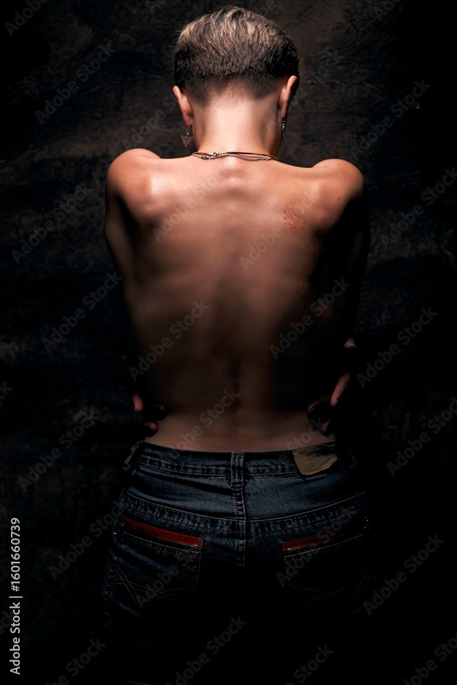 Fototapeta premium A woman with short, blonde hair stands with her back to the viewer