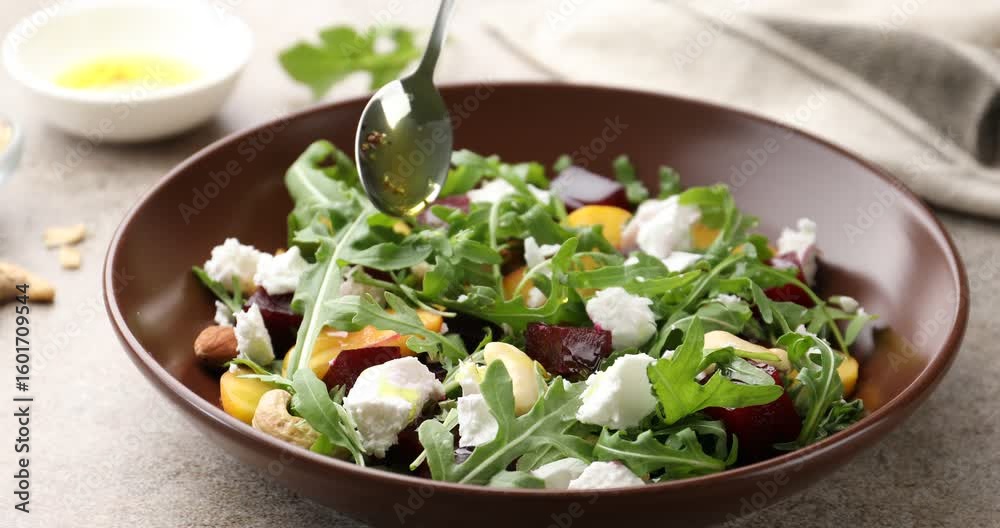 Woman adding oil to tasty salad with arugula at grey table, closeup