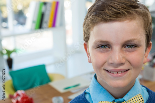 Male child studying in home study area by window with notebook and green pen, copy space