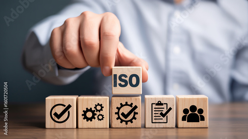 Hand Placing ISO-Labeled Wooden Cube on Row of Wooden Blocks – Close-Up Concept