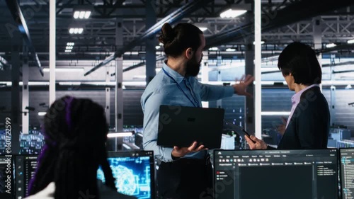 Data center manager supervising work done by programmers working on neural network software. Server hub supervisor overseeing IT staff members implementing deep learning tech, camera A
