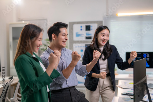 Three people are standing in front of a computer monitor