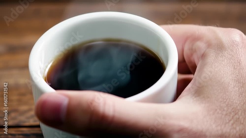 Steaming cup of coffee held in hand