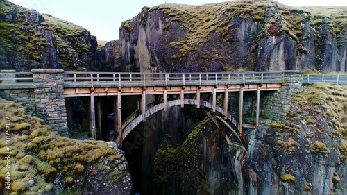 Wooden bridge spanning a deep gorge between moss-covered cliffs