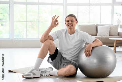 Young man sitting on yoga m...