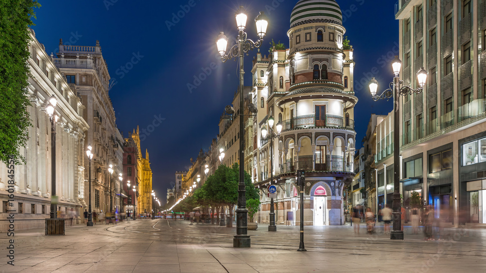 Naklejka premium Illuminated Adriatica building on Avenida de la Constitucion at night, Seville, Spain