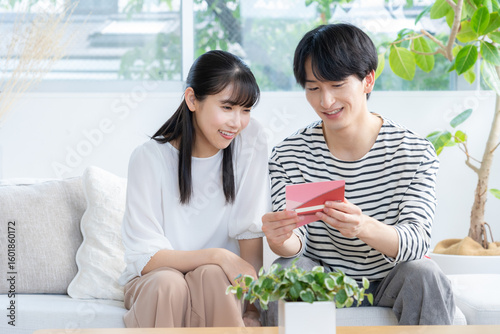 Foto リビングで通帳を見る若い夫婦