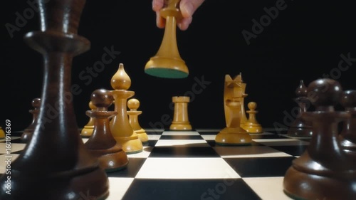 Player hand moving white queen chess piece on a chessboard