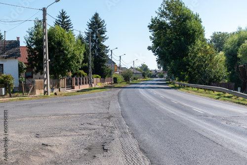 Fototapeta Naklejka Na Ścianę i Meble -  Asphalt road with power lines in a small Hungarian village