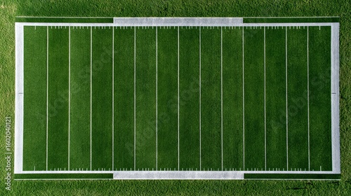 Top-down view of football field with precision-cut grass and bright hash marks sun directly overhead casting short crisp shadows