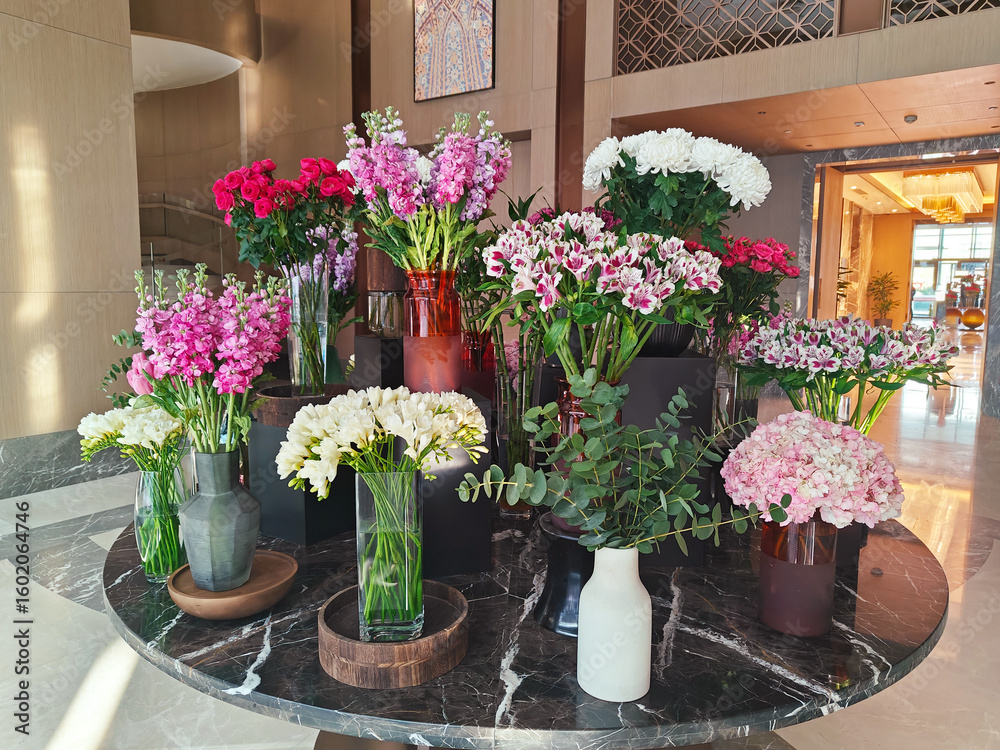 Naklejka premium Vibrant floral arrangement in modern lobby showcasing diverse blooms and elegant vases