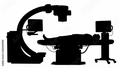 Silhouette of a patient lying on a medical table with x ray equipment and monitors in a dark room