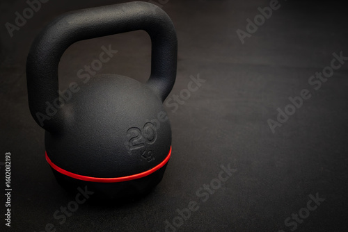 Black kettlebell on dark gym floor. Fitness and strength training