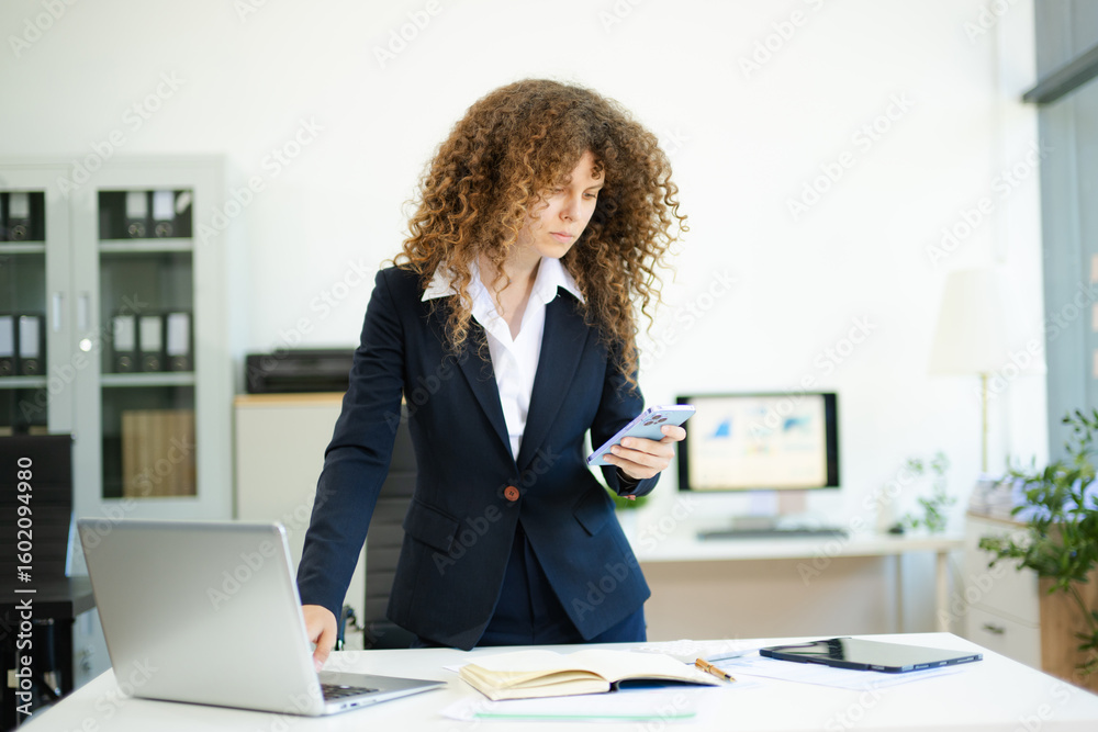 Obraz premium Confident businesswoman working with laptop and tablet in office