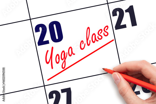 20th day of the month.  Hand writing Yoga class reminder and drawing a line on calendar with red pen on white background. Concept of sport and fitness activity.  Planning and scheduling