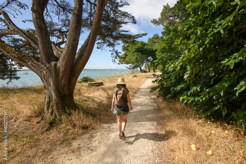 femme seule de dos, sur un chemin de randonnée au bord de la mer sur l'ile d'oléron en France