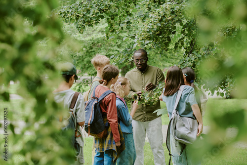 Foto Black middle aged man teaching group of multiethnic children outdoors in park, c