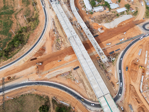 The construction site before the construction of the concrete bridge over the intersection by crane workers, tractors, and backhoes