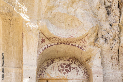 Primitive red-ochre Byzantine fresco in rock-carved arch at medieval monastery in Goreme Open Air Museum, Cappadocia, Turkey