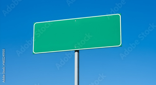Blank green road sign against a clear blue sky, perfect for your message or advertisement, easily customizable for any branding needs.