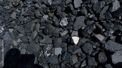 A close-up of dark gray gravel and small stones scattered across a rough, uneven surface, with subtle texture and natural lighting highlighting the granular details