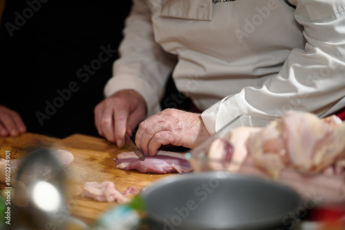 Professional chef precisely slicing raw meat during culinary class